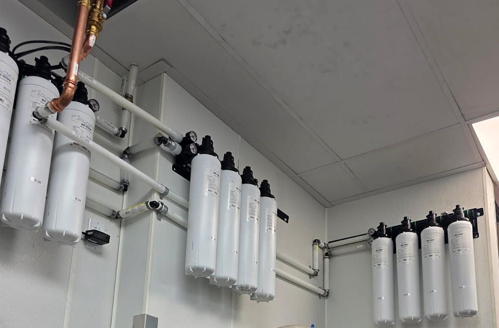 Aquamor filtration cartridge banks installed across a store equipment room